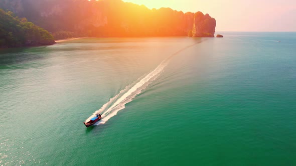 4K aerial view over a ship sailing at sea, mountains in the background.