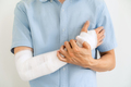 Young man with gauze bandage wrapped around injury hand on white background - PhotoDune Item for Sale