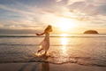 Young woman traveler dancing and enjoying beautiful Sunset on the tranquil beach - PhotoDune Item for Sale