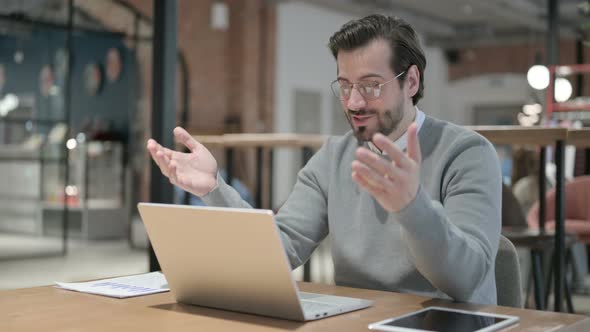 Young Man Talking on Video Call on Laptop in Office