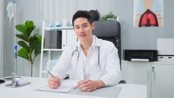 Portrait of Asian male doctor sit on office working table in hospital.