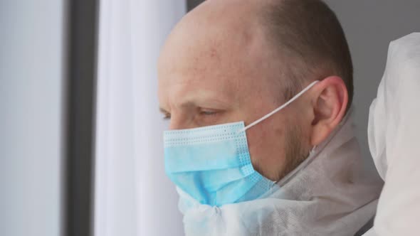 Closeup of an Infectious Disease Doctor in Protective Clothing Takes Off His Mask and Goggles After