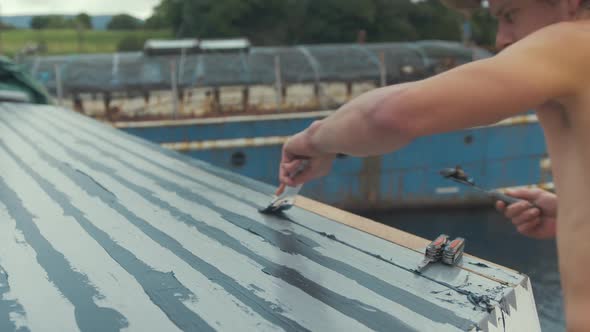 Mid shot flattening sika flex sealant on roof of masked wooden boat cabin roof planking.