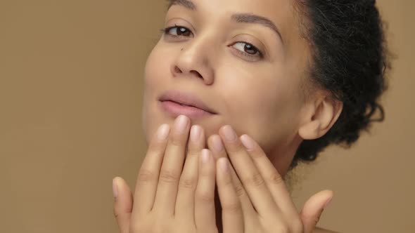 Beauty Portrait of Young African American Woman Gently Touching Face with Fingers and Giving Skin