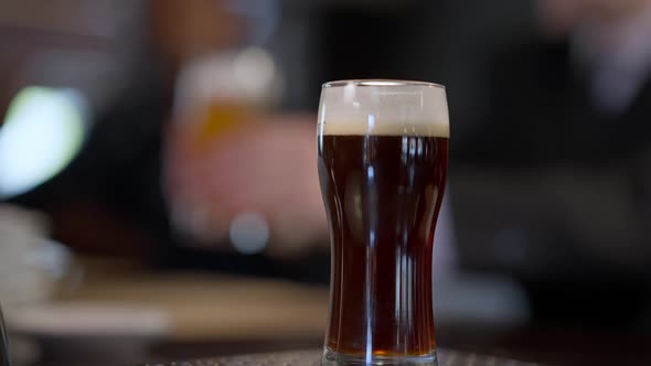 Closeup Beer Glasses on Bar Counter with Male Hand Taking Pale and Dark Lager Blurred Men Clinking