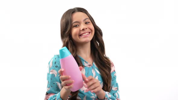 Happy Child Girl with Long Curly Hair Offer to Use Skin Body Lotion Bottle Skincare