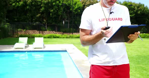 Lifeguard holding clipboard and looking at stop watch