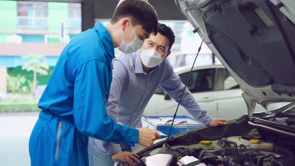 Asian automotive mechanic listen to client man explain car condition.