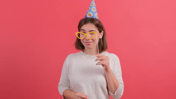 Happy Young Woman in Party Hat Holding Birthday Accessories on Red Background.