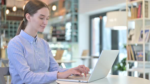 Thumbs Up By Young Businesswoman Using Laptop in Cafe