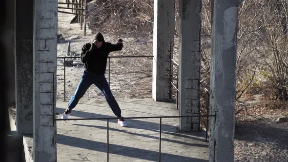 Boxer training outdoors in an abandoned building. Fulfills blows, shadow boxing.