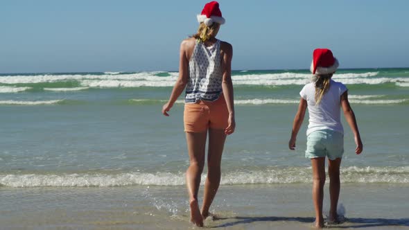 Mother and daughter walking on shore at beach on a sunny day