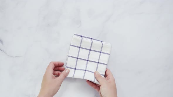 Folding black and white patterned paper towels on marble surface.