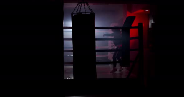 A boxer boxing with a shadow draws quick punches in a semi-dark ring with a backlight