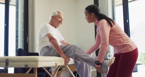 Video of biracial female physiotherapist examining caucasian senior man