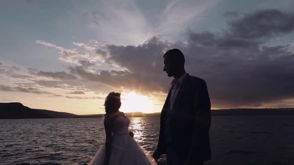 Newlyweds Couple on a Mountainside By the Sea. Sunset. Groom and Bride