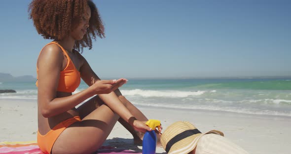 African American woman applying sunscreen at beach