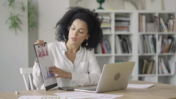 Portrait of a Young African American Woman Talking on Video Conference Call Using Laptop and Headset