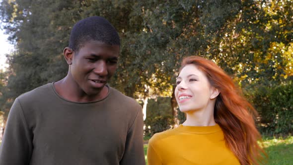 Interracial love concept.Young mixed race couple walking and talking in the park