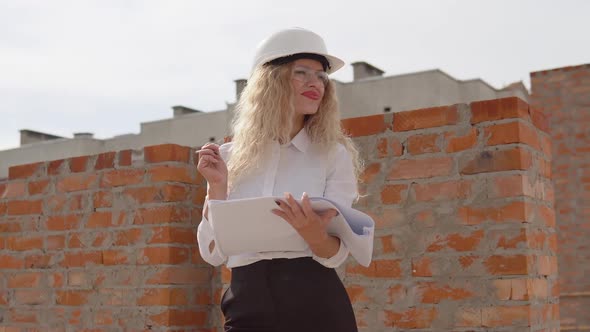 Female Architect in Business Attire Standing Outdoors at Construction Site