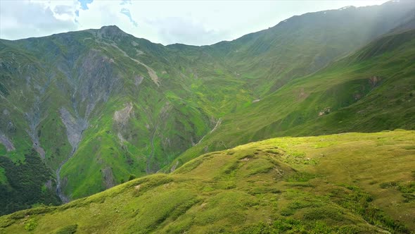 Aerial drone view of nature in Georgia. Caucasus Mountains, greenery, valleys, lush clouds, shack on