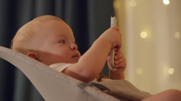 Little Boy Sits in Rocking Chair and Watching TV