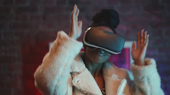 Young Cheerful African Woman in Faux Fur Coat and Vr Glasses Dancing Indoors