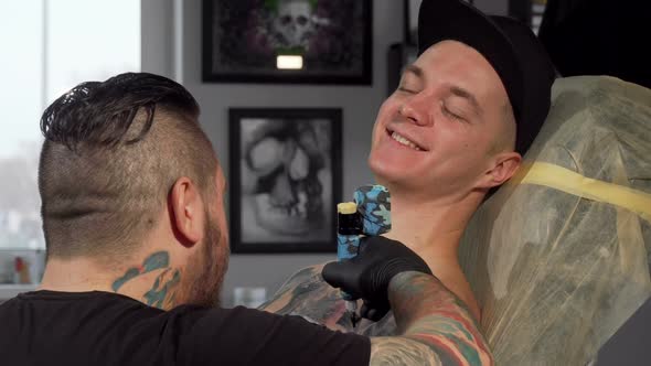 Cheerful Young Man Smiling To the Camera, While Getting Tattooed