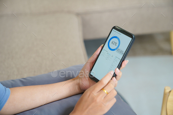 Woman controlling smart home. mobile phone with smart home app in living room.