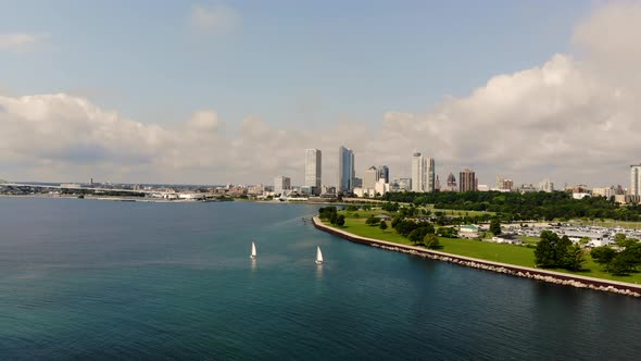 Aerial pan of sailboats in quiet bay with city skyline in the background