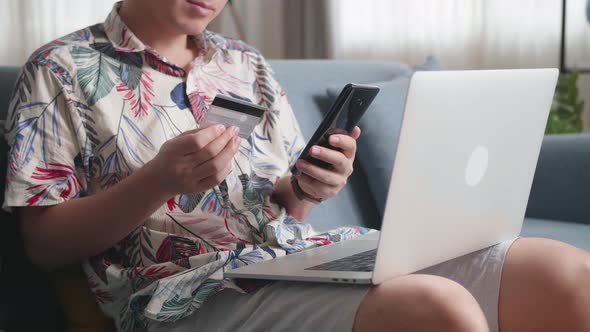 Close Up Of Hand Holding Credit Card And Using Smartphone Shopping Online In Living Room