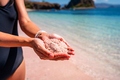 Young woman tourism holding sand at the tropical pink sandy beach at Komodo islands in Indonesia - PhotoDune Item for Sale