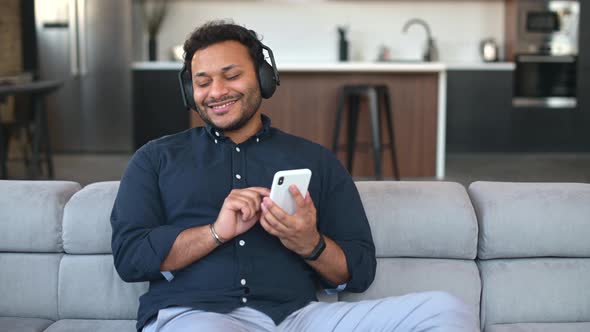 Multiethnic Hindu Guy in Headphones Listening Music at Home