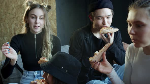 Young Dancers are Sharing the Last Piece of Pizza Sitting on the Couch