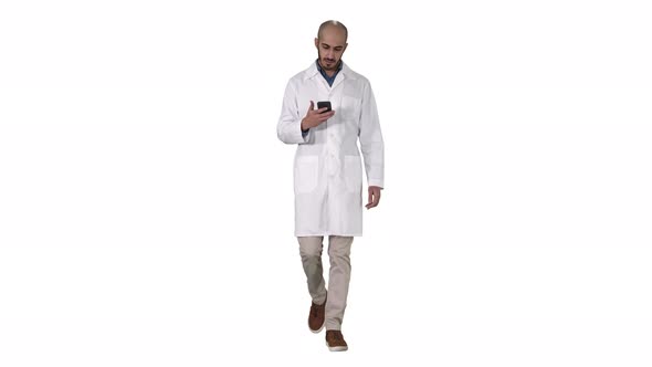 Male Arab Doctor Texting Message on the Phone While Walking on White Background.