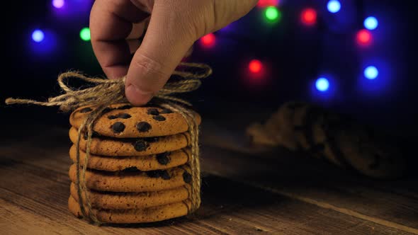 Hand Puts a Stack of Chocolate Chip Cookies on Wooden Table