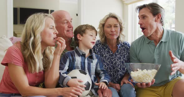 Happy caucasian family watching tv and supporting in living room