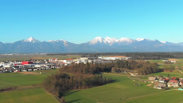 Aerial view flying up over the town of Skofja Loka in Slovenia with Alp mountains opening in the bac