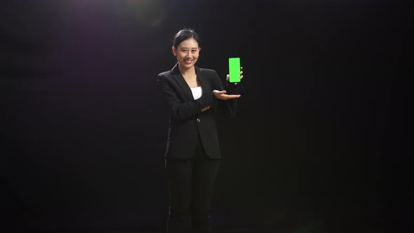 Speaker Woman Holding And Pointing Green Screen Smartphone In The Black Studio