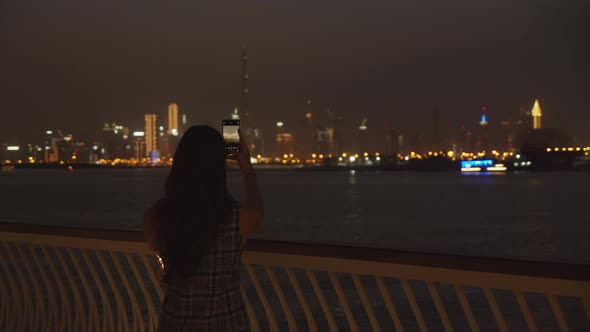 Woman Taking Pictures of Dubai Skyline at Night