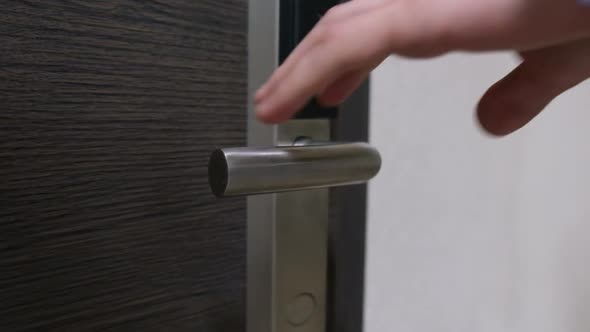 A Man Takes a Shiny Door Handle and Opens a Modern Beautiful Door