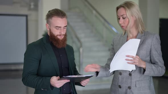 Serious Female CEO Passing Paperwork to Concentrated Bearded Male Employee in Slow Motion