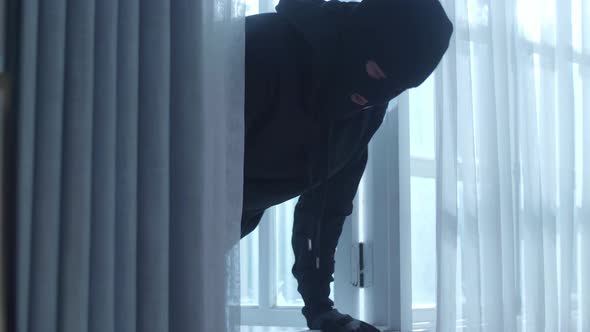 Close Up Of A Thief Man Holding Flashlight Opening Window And Entering Someone's House