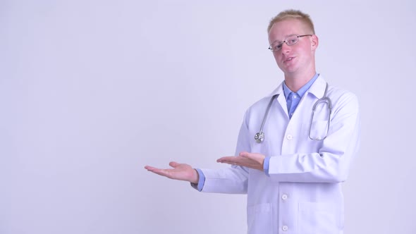 Happy Young Blonde Man Doctor Showing Something