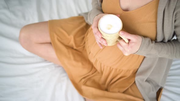 Cute Pregnant Woman Holds in Hand a Cup of Coffee