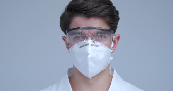 Portrait of Handsome Doctor or Scientist Wearing a White Coat and Mask and Protection Glasses