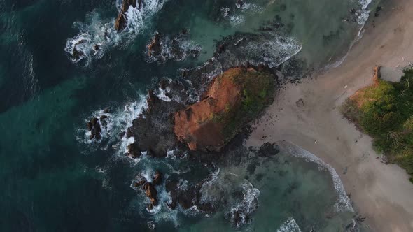 Still aerial footage of a beautiful rocky beach in Costa Rica. Small sandy peninsula at sunset. Warm