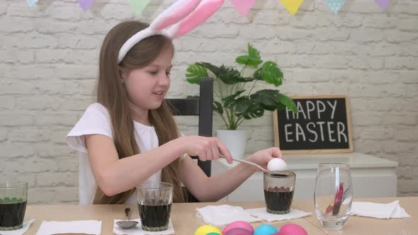 Little Girl in Bunny Ears Painting Eggs for Easter