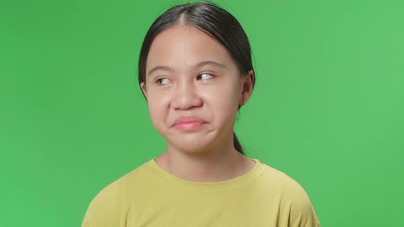 Young Asian Kid Girl Emotionally Flipping Something While Standing In The Green Screen Studio