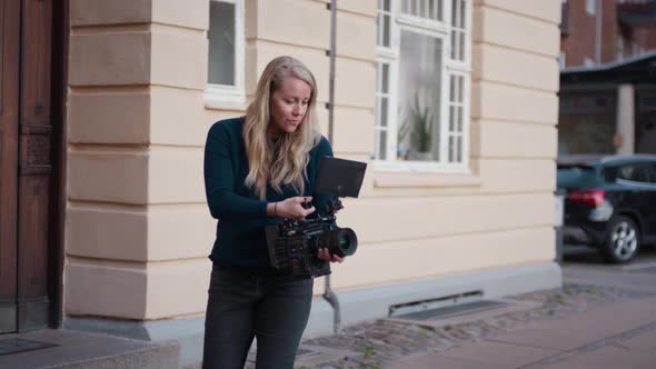 Female Film Maker Focusing Camera In Street